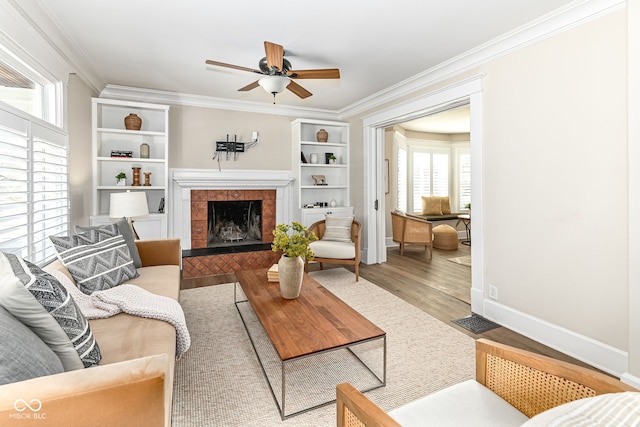 living room with hardwood / wood-style floors, ceiling fan, crown molding, and a tile fireplace