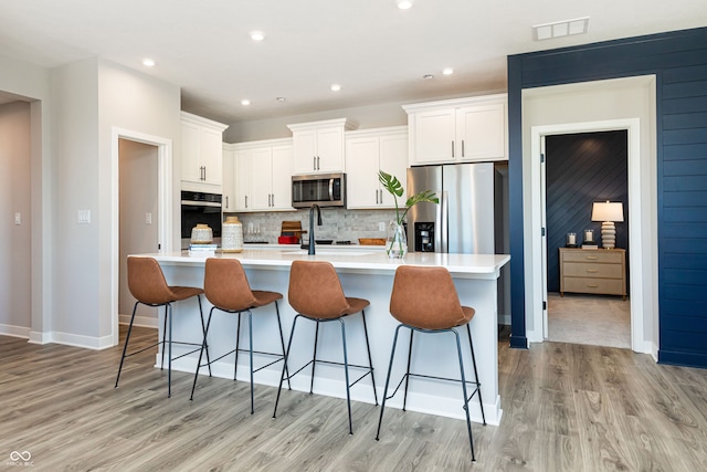 kitchen with a large island, appliances with stainless steel finishes, light wood-type flooring, and white cabinetry