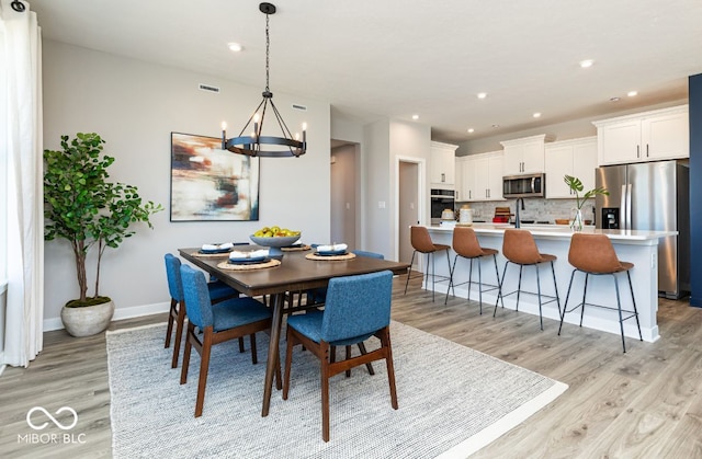 dining area with light hardwood / wood-style flooring and a notable chandelier