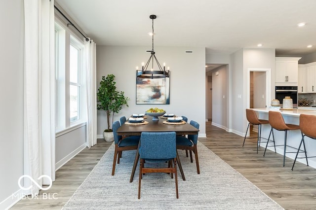 dining room with a healthy amount of sunlight, light hardwood / wood-style flooring, and a chandelier