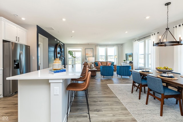 kitchen with white cabinets, stainless steel fridge, a healthy amount of sunlight, and light wood-type flooring