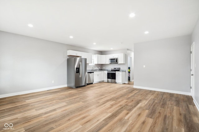 kitchen with light hardwood / wood-style floors, white cabinetry, and appliances with stainless steel finishes