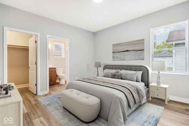 bedroom with connected bathroom and light hardwood / wood-style floors