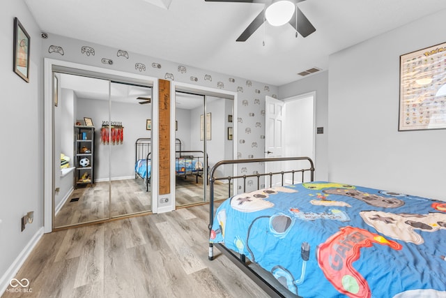 bedroom featuring wood-type flooring, two closets, and ceiling fan