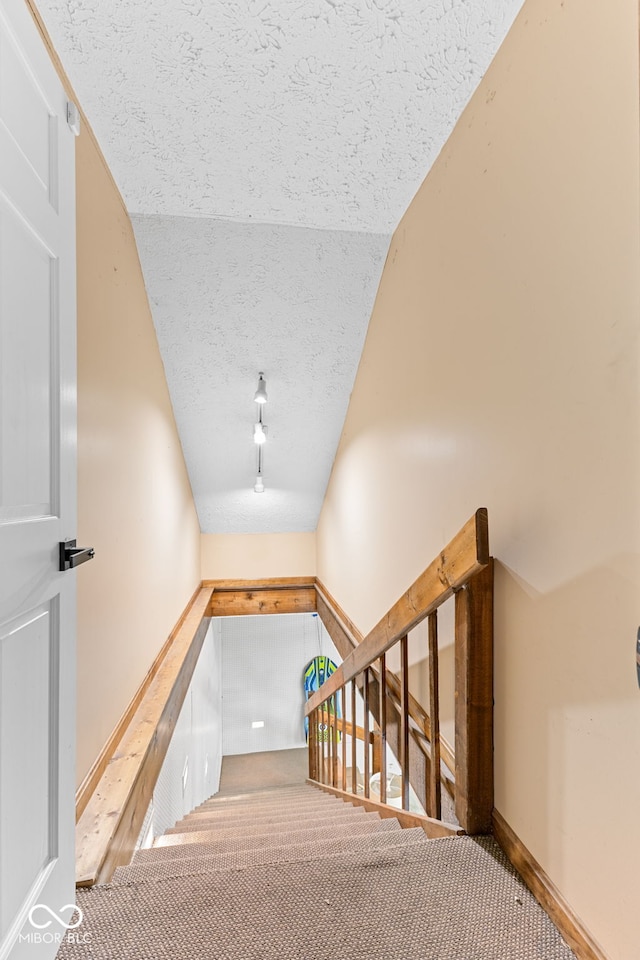 stairway with carpet floors and vaulted ceiling