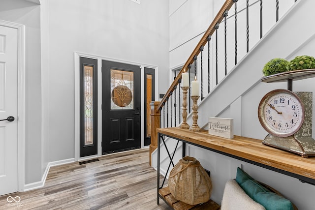 entrance foyer featuring a towering ceiling and light hardwood / wood-style floors