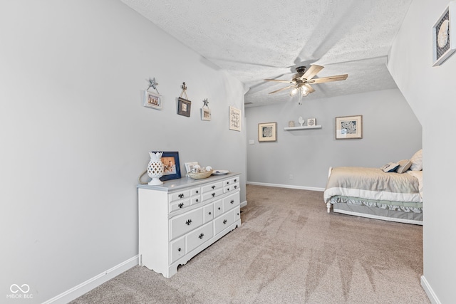 bedroom with ceiling fan, light colored carpet, and a textured ceiling