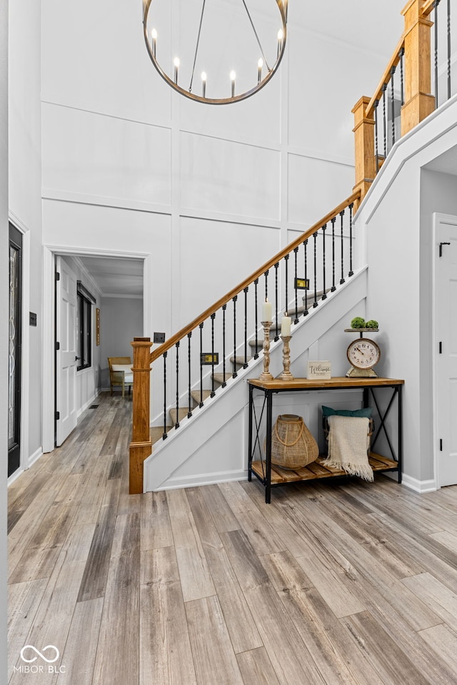 stairway featuring hardwood / wood-style flooring, a high ceiling, and a chandelier