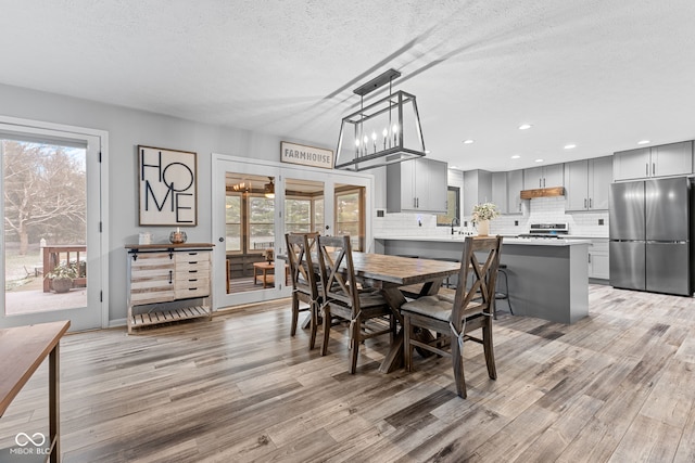 dining area featuring a textured ceiling, plenty of natural light, light hardwood / wood-style floors, and french doors