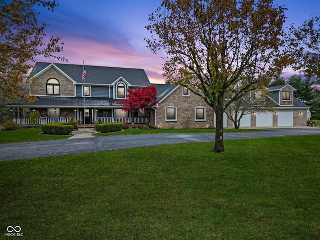 view of front facade with a lawn, a porch, and a garage