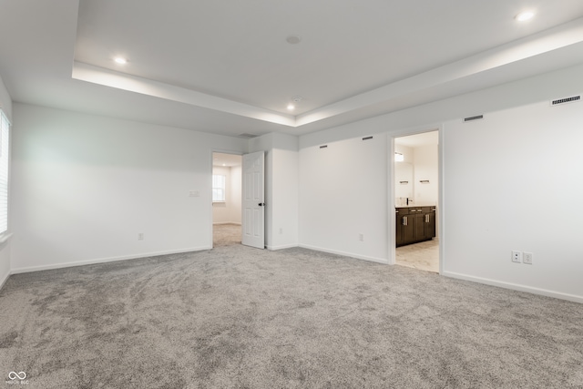 spare room featuring a tray ceiling and light carpet