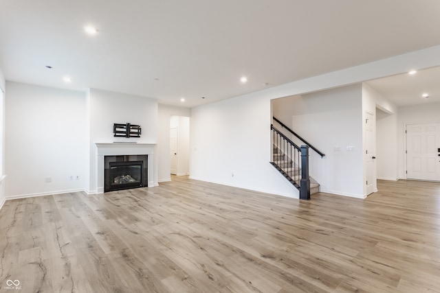 unfurnished living room featuring light wood-type flooring and a tiled fireplace