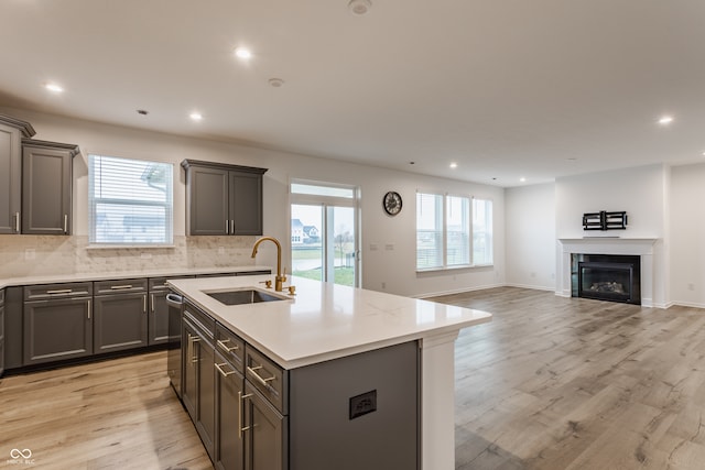 kitchen featuring a healthy amount of sunlight, a center island with sink, light hardwood / wood-style flooring, and sink