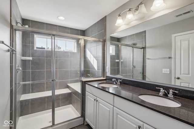 bathroom featuring a shower with door and vanity