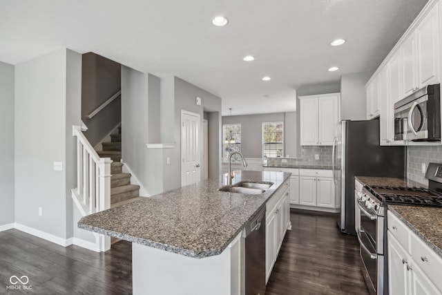 kitchen featuring an island with sink, stainless steel appliances, sink, white cabinetry, and dark hardwood / wood-style flooring