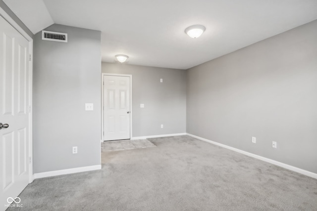 spare room featuring vaulted ceiling and carpet floors