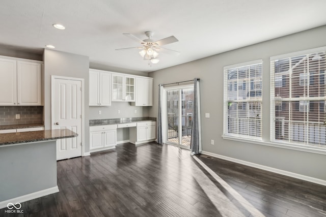 kitchen with backsplash, white cabinetry, ceiling fan, dark stone countertops, and dark hardwood / wood-style floors