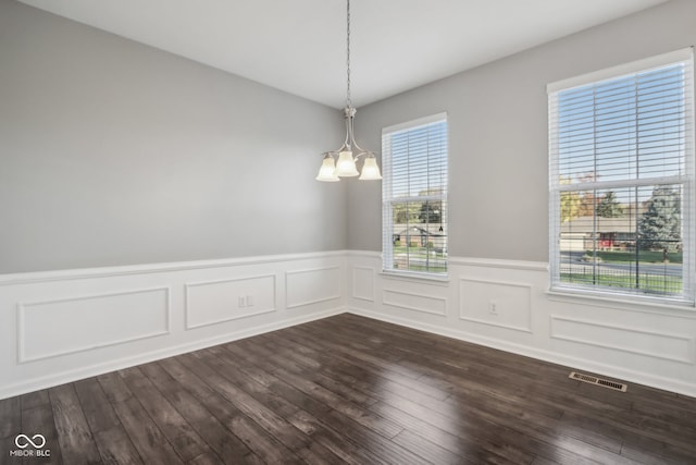 spare room featuring a chandelier and dark hardwood / wood-style floors