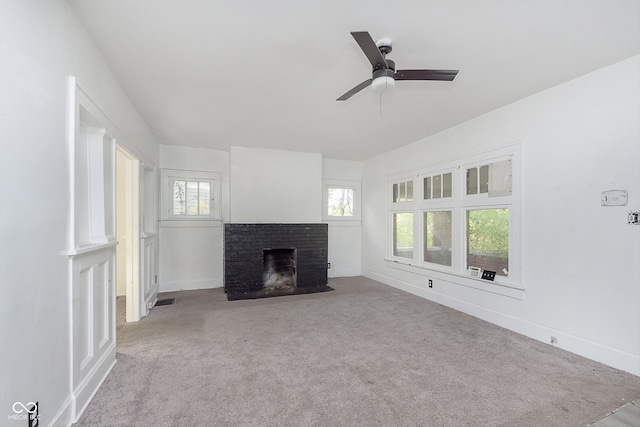 unfurnished living room featuring a brick fireplace, light colored carpet, and ceiling fan