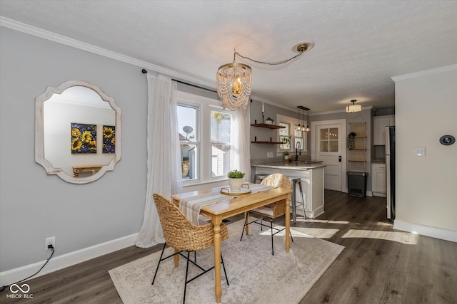 dining space with a textured ceiling, dark hardwood / wood-style floors, crown molding, and a chandelier