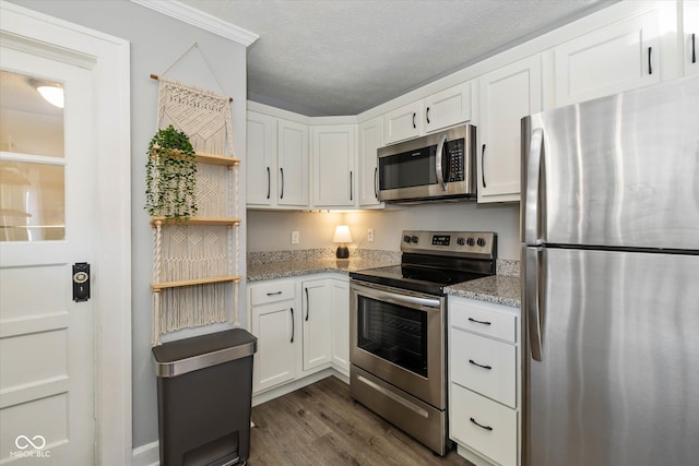 kitchen with dark wood-type flooring, light stone countertops, a textured ceiling, white cabinetry, and stainless steel appliances