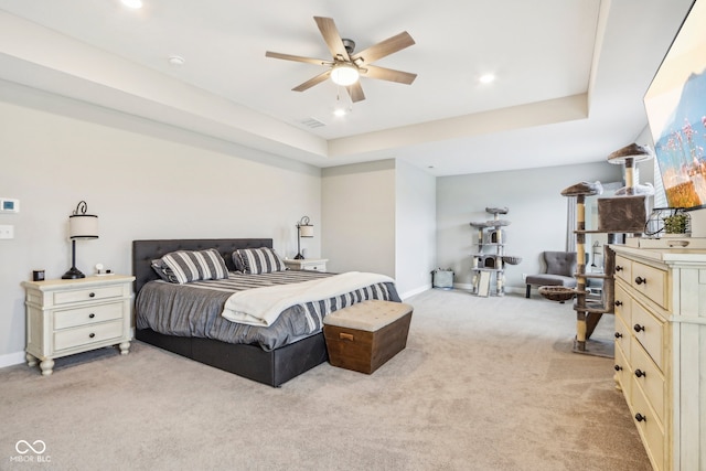 bedroom featuring ceiling fan, light carpet, and a tray ceiling