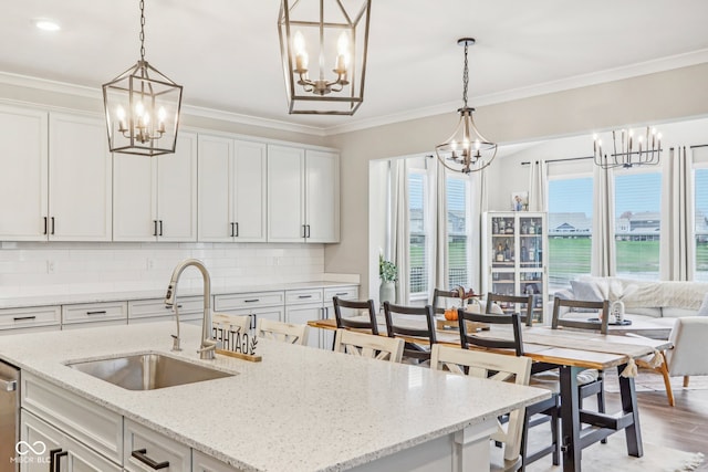 kitchen featuring white cabinets, an island with sink, a healthy amount of sunlight, and sink