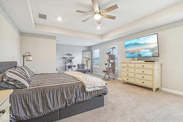 carpeted bedroom with a tray ceiling and ceiling fan