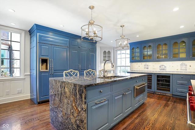 kitchen featuring wine cooler, a wealth of natural light, an island with sink, and blue cabinets