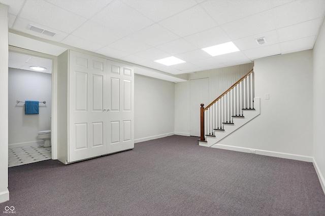 basement with dark colored carpet and a drop ceiling