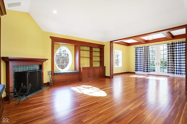 unfurnished living room with a fireplace, french doors, hardwood / wood-style flooring, and plenty of natural light