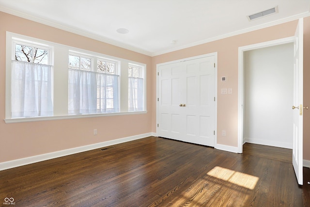 unfurnished bedroom featuring ornamental molding, a closet, and dark wood-type flooring