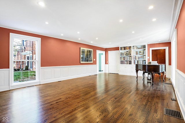 living room with built in shelves, dark hardwood / wood-style floors, and ornamental molding