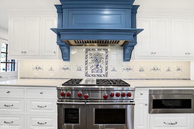 kitchen featuring premium range hood, decorative backsplash, white cabinetry, and stainless steel appliances