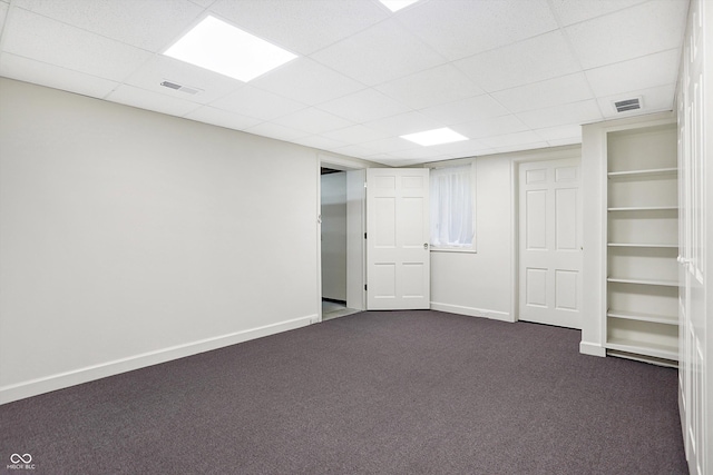 basement featuring dark colored carpet and a paneled ceiling