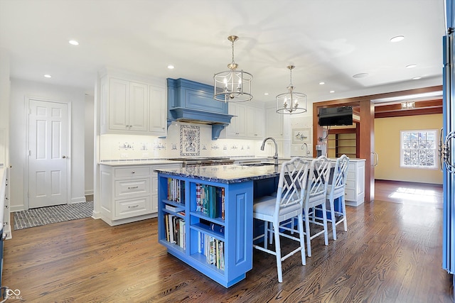 kitchen with white cabinetry, a kitchen island with sink, dark wood-type flooring, and blue cabinets