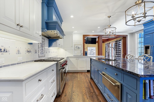 kitchen with pendant lighting, a center island with sink, blue cabinets, stainless steel stove, and white cabinetry