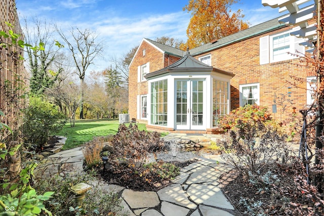 rear view of property with a lawn, a sunroom, and french doors