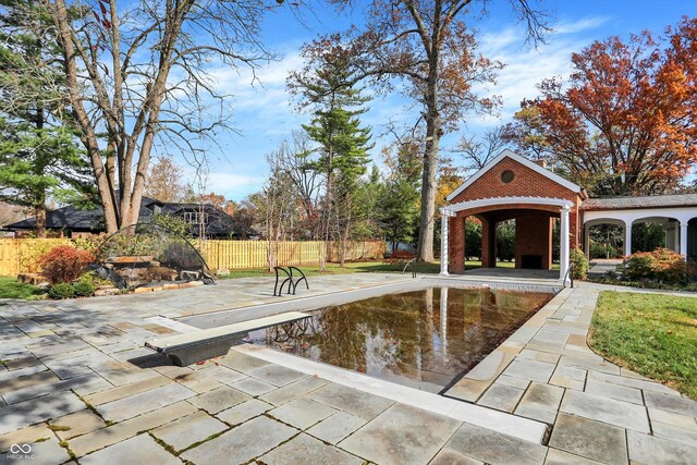 view of pool with a patio and a diving board