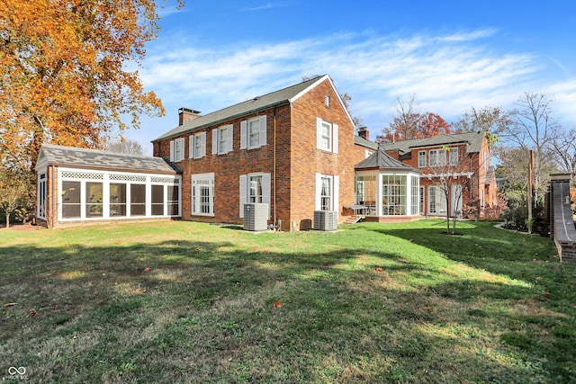 back of property featuring a sunroom, central AC unit, and a yard