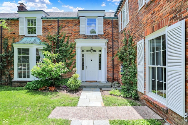 2505 Riverside Dr, Columbus, IN 47201 - view of exterior entry with brick siding, a chimney, and a yard