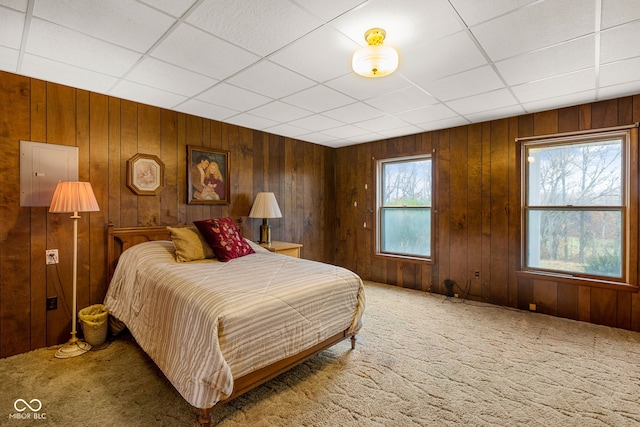 carpeted bedroom with a paneled ceiling and wooden walls