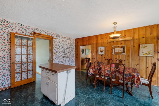 dining room featuring a textured ceiling and wooden walls