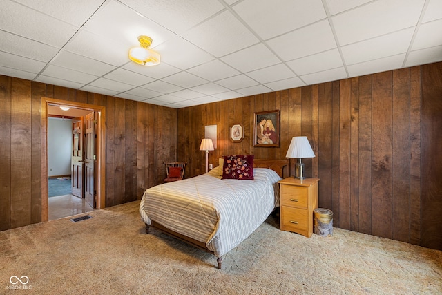 bedroom featuring wood walls, carpet, and a drop ceiling