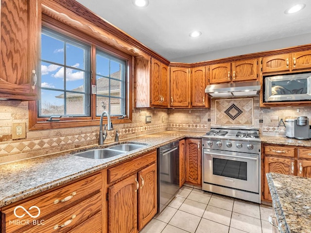 kitchen featuring decorative backsplash, light stone countertops, stainless steel appliances, sink, and light tile patterned flooring