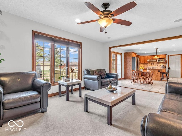 living room with a textured ceiling, light colored carpet, and ceiling fan