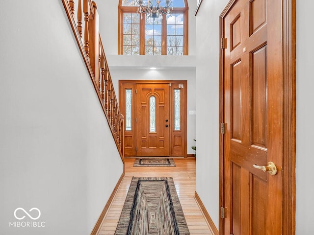 foyer entrance featuring a high ceiling, light wood-type flooring, and a notable chandelier