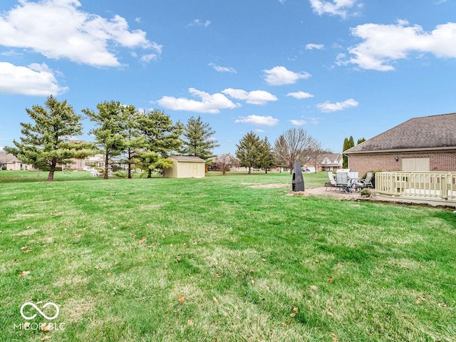 view of yard featuring a patio, a storage unit, and a wooden deck