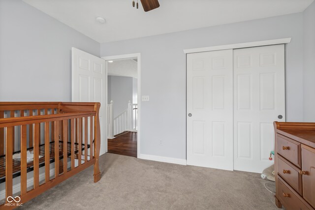 bedroom featuring a nursery area, light colored carpet, a closet, and ceiling fan