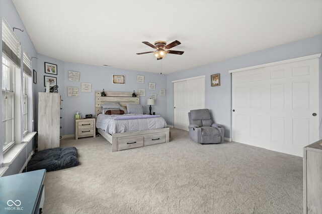 carpeted bedroom featuring ceiling fan and multiple closets